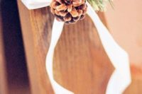 08 a pinecone with evergreens and white ribbon to decorate the aisle