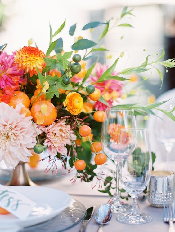 a bold centerpiece with colorful blooms, foliage and citrus for a bold tropical wedding