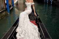 12 a bride wearing an off the shoulder lace applique wedding dress with a long train and statement earrings