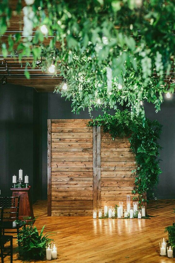 a reclaimed wood backdrop with cnaldes and lots of greenery on its corner