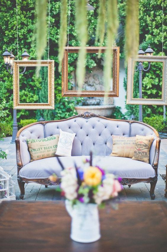 a wedding lounge with a lilac sofa and hanging picture frames over it for a chic feel