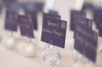 15 tiny Christmas ornaments with faux snow inside are amazing for displaying escort cards