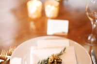 16 a place setting with evergreens and a gilded pinecone for a winter feel