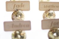 18 gold sequin ornaments with place cards held is a cool and glam idea for a winter wedding