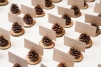 22 pinecone place card holders on thin wood slices are very easy to make and won’t cost a thing
