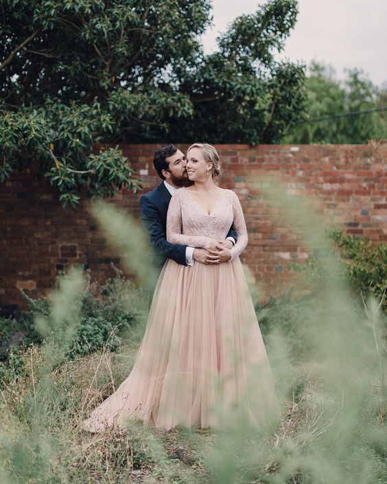 a dusty pink wedding dress with an embroidered sparkling bodice, long sleeves and a layered skirt