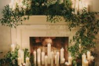 24 a fireplace covered with lush greenery,, lots of candles and tree stumps