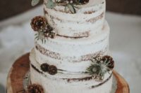 24 a semi-naked wedding cake with leaves, blooms and pinecones and wood slice toppers