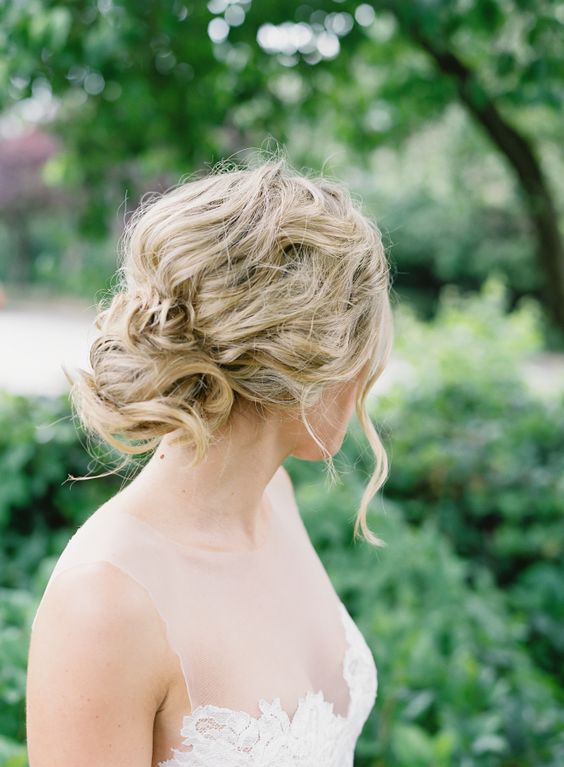a messy wavy and twisted updo for an effortlessly chic bride