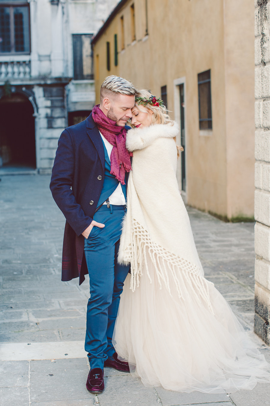 The groom wearing a bold blue suit, a navy coat, burgundy moccasins and a burgundy scarf