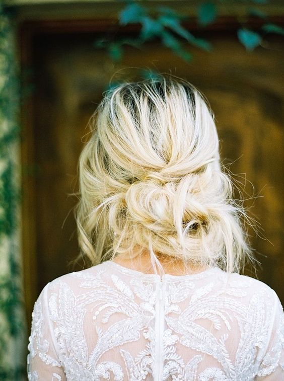 a very messy low updo with twists and bangs for an effortlessly chic look