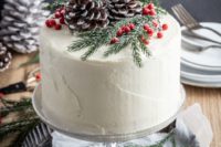 27 a winter frosted wedding cake topped with berries, evergreens and snowy pinecones