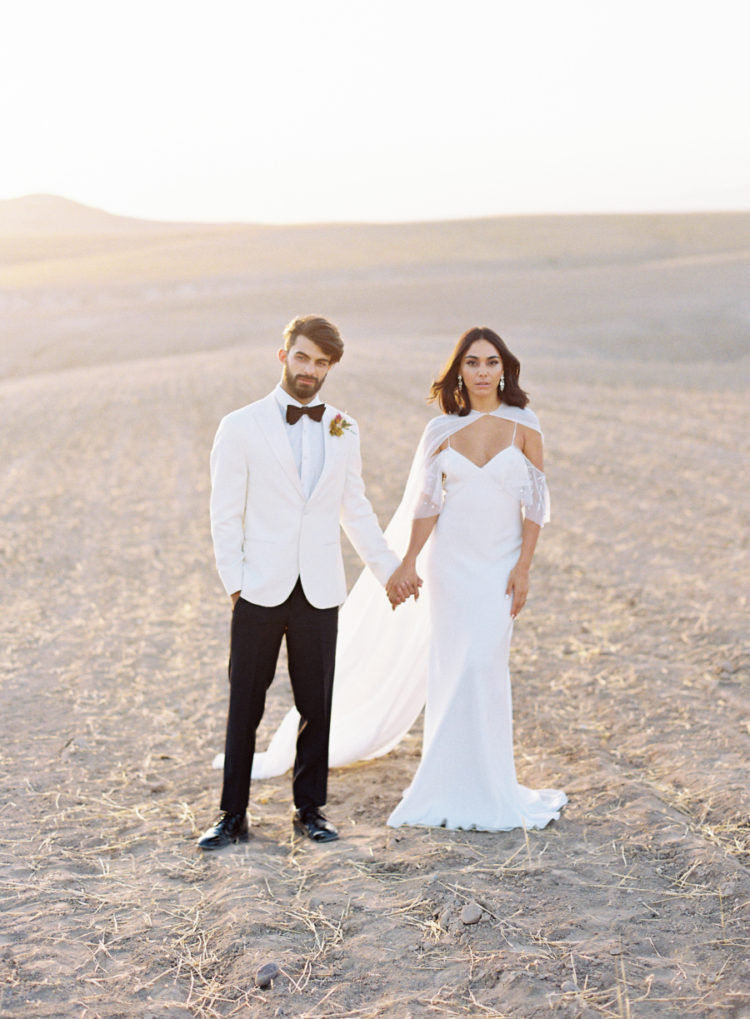 The first bridal look was done with a cold shoulder weddding gown and an airy cape, the groom was wearing a fresh take on a white tux