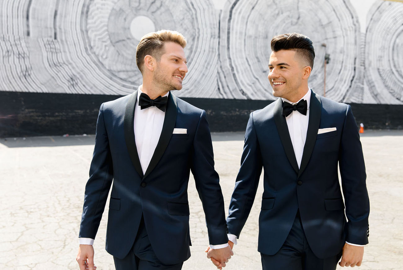 The grooms were wearing navy tuxedos with black lapels and matching hairstyles