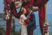 04 a gorgeous wedding arch with burgundy draperies, pink, fuchsia and red blooms
