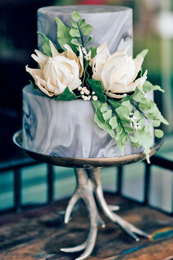 a grey marble wedding cake with edible leaves and blooms looks very interesting