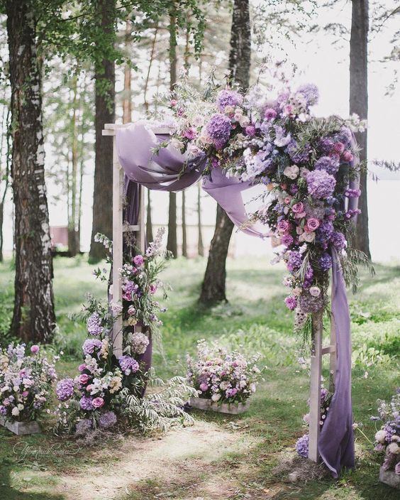 a fantastic floral arch with lilac draperies and lush blooms in purple shades on the corner and down