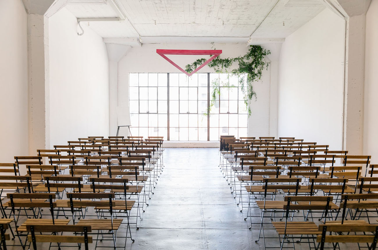 The ceremony space was a white one with a greenery and a pink triangle altar