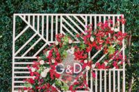06 a modern geometric backdrop with a lush red flower cascading garland and monograms