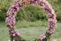 07 a bold circle floral arch in the shades of pink and lilac and some candles around