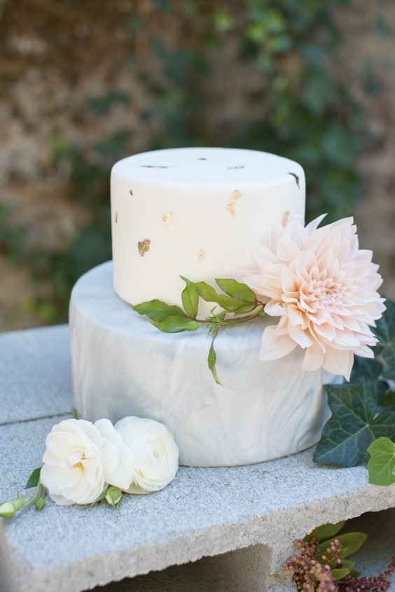 a modern wedding cake with a grey marbleized layer and a white gold leaf layer plus a large bloom