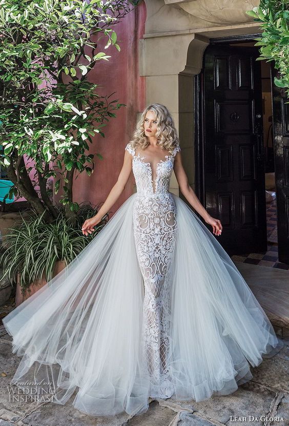 a textural lace sheath wedding dress with a plunging neckline, cap sleeves and a layered tulle skirt