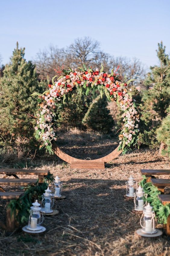 a large wooden arch covered with pink and red flowers and greenery will make a statetment