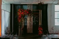 14 a copper wedding arch with lush red blooms and candles hanging for an industrial wedding