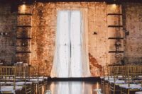 14 the ceremony space with shabby brick walls, lights, petals and a gol chandelier