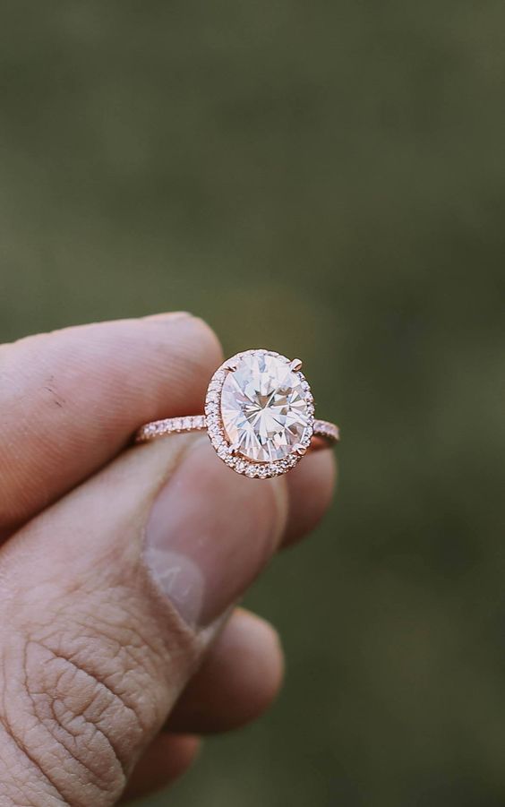 a rose gold engagement ring with an oval-shaped diamond and a halo around