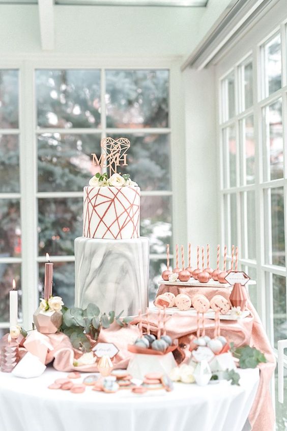 a modern wedding cake with a marble layer and a copper geo one with a geometric topper