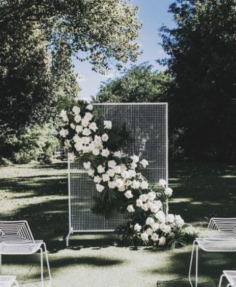 white wire wall and a lush floral and greenery decoration attached diagonally