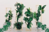 17 wooden pillars with tropical leaves and blooms and acrylic chairs with palm leaves for a modern tropical wedding