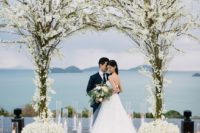 18 a floral arch composed of two trees and white blooms and white blooms to line up the aisle