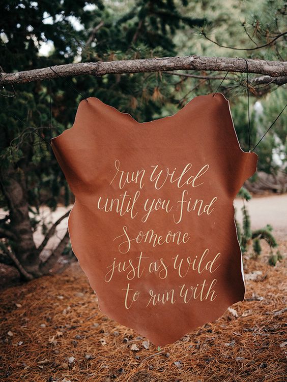 a hand lettered leather sign for an outdoor rustic, camping or woodland wedding
