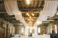 18 an industrial loft with brick walls, airy white fabric and white petals on the aisle
