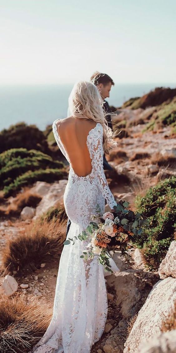 a backless lace applique wedding dress with long sleeves and a small train is very sexy and chic