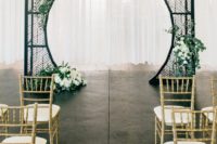 19 a black forged arch with a round cutout and greenery and white blooms for a modern ceremony