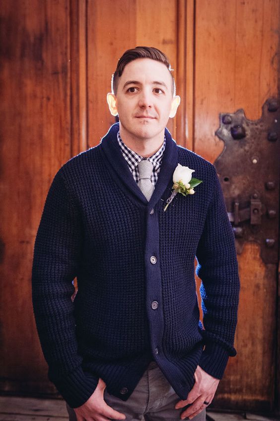a navy gingham shirt under thick navy shawl cardigan and neutral pants for a mountain lodge wedding