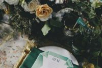 22 emerald napkins, drink stirrers, gold cutlery and gold rim glasses with a lush floral centerpiece