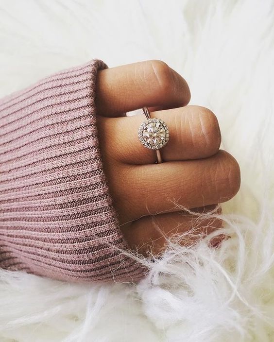 a round diamond engagement ring with a halo around looks girlish and chic