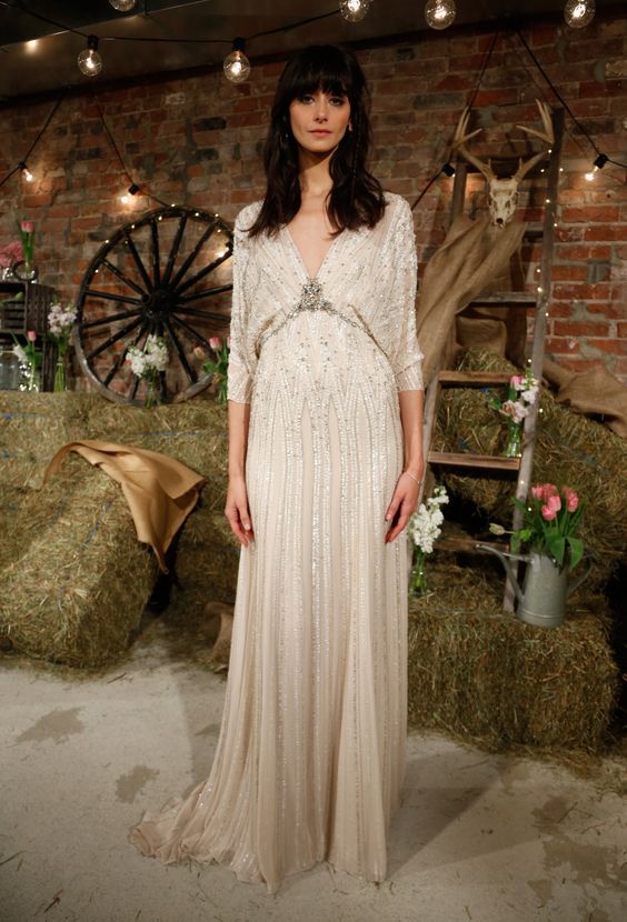 a heavily embellished wedding dress with long sleeves, a deep V-neckline shows retro glam