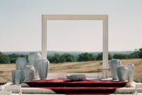 24 a natural backdrop with a minimalist white arch and vases around the arch