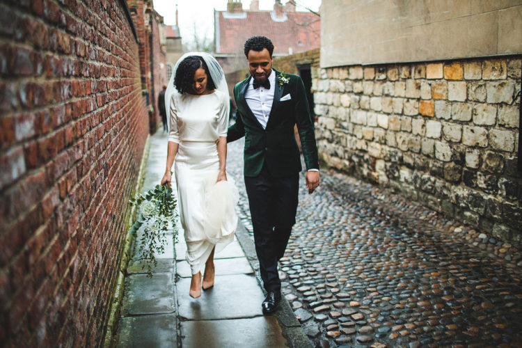 an edgy modern groom's look with black trousers, a white shirt, an emerald velvet jacket and a matching bow tie