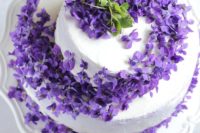 26 a white wedding cake with violet blooms on top and some greenery is ideal for a summer wedding