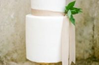 27 a white wedding cake with a blush ribbon and foliage for a cute and chic look