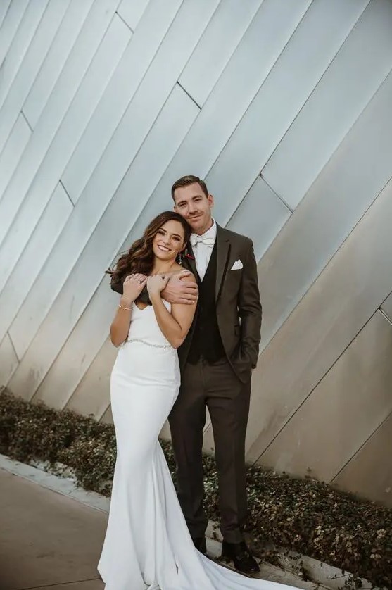 a beautiful modern mermaid plain wedding dress with a V-neckline, a train and an embellished belt is amazing