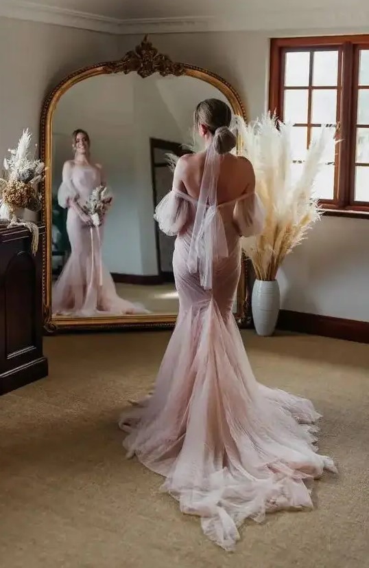 a blush off-the-shoulder mermaid wedding dress with puff sleeves and a train plus a blush wrap for the hair