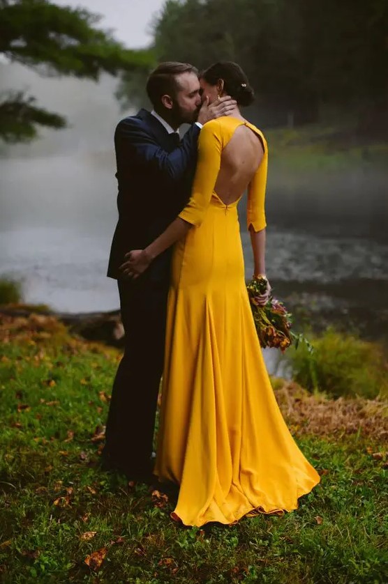 a bold yellow mermaid wedding dress with long sleeves and a cutout back is a modern and very bold idea for summer or fall bride