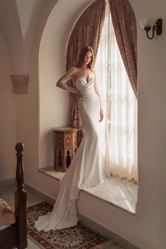 a catchy strapless mermaid wedding dress with a draped bodice and a plain skirt with a train, a sheer pearl bodysuit under it
